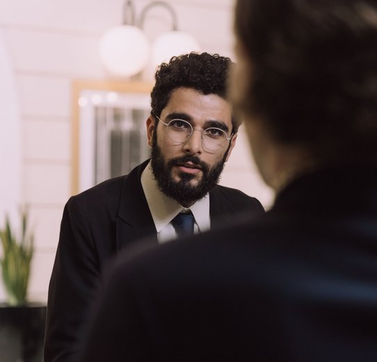 A professional businessman checks in at a hotel reception, engaging with a concierge.