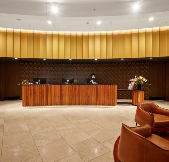 Hotel reception area featuring a large wooden wall, modern furnishings, and a welcoming atmosphere for guests.