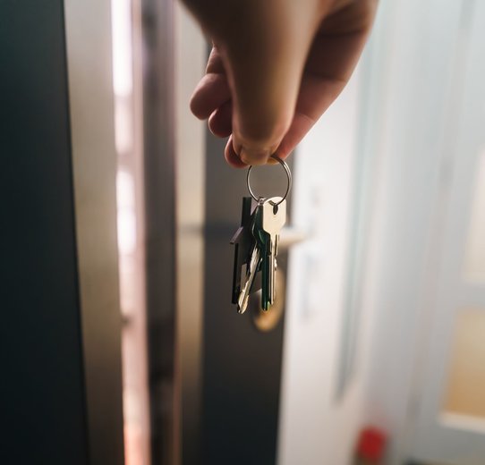 A hand holding two keys, indicating readiness to unlock a door, signifying access and transition.