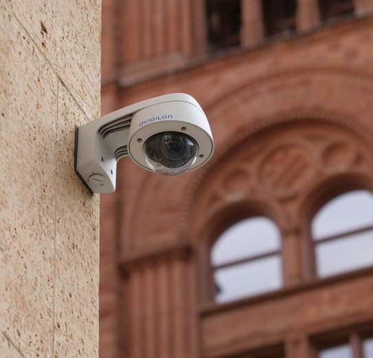 Security camera mounted on a building's exterior, monitoring the surrounding area for safety and surveillance purpose
