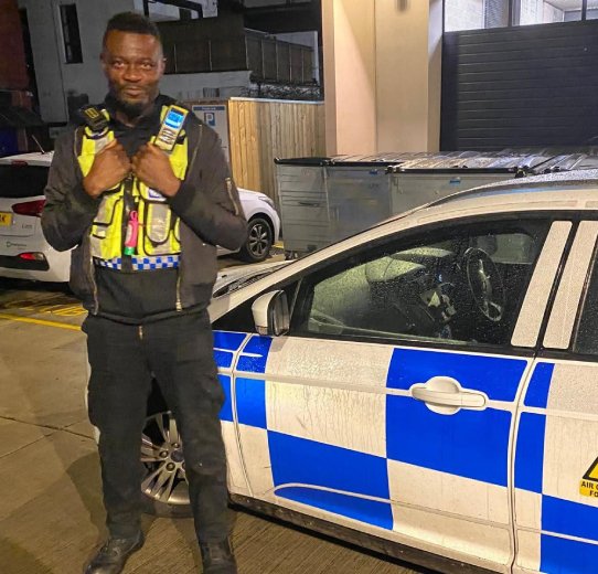 A man stands next to a police car, highlighting the vehicle's design and the official police insignia.